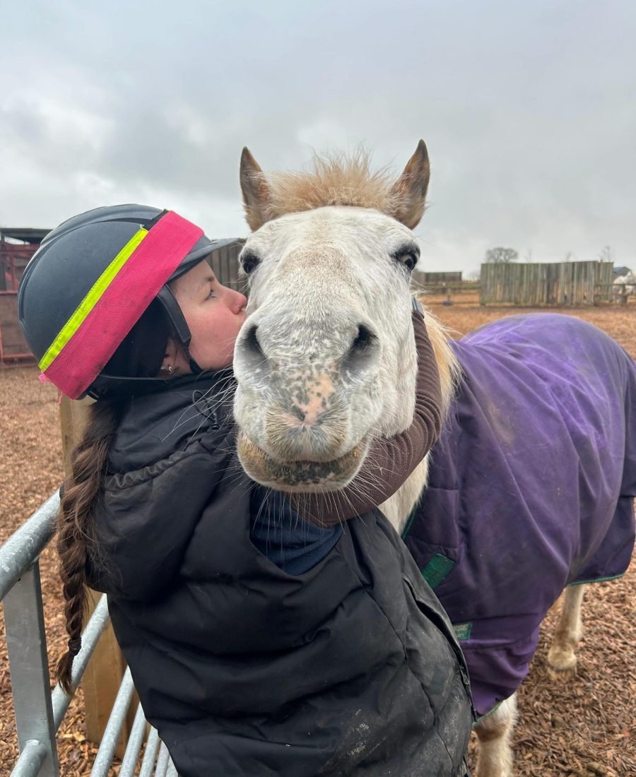 Annabel with a grey pony in a purple rug